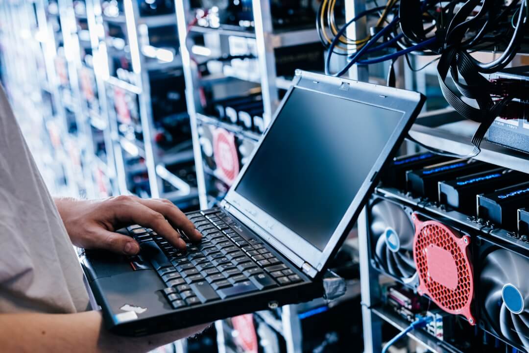 IT specialist working on computer in bitcoin and crypto currency mining farm.